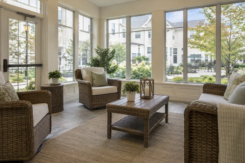 Indoor sunroom with wicker seating and simple courtyard view